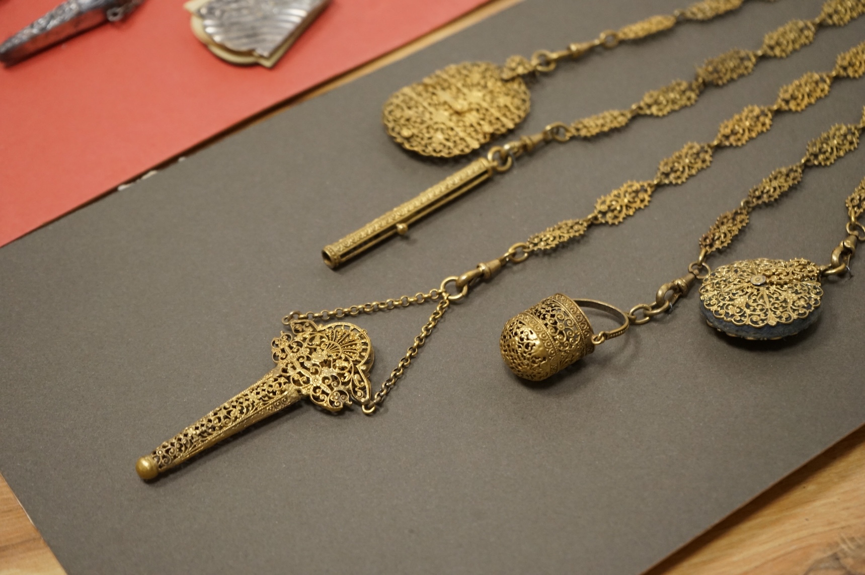 Four assorted 19th century base metal chatelaines, one with some silver implements